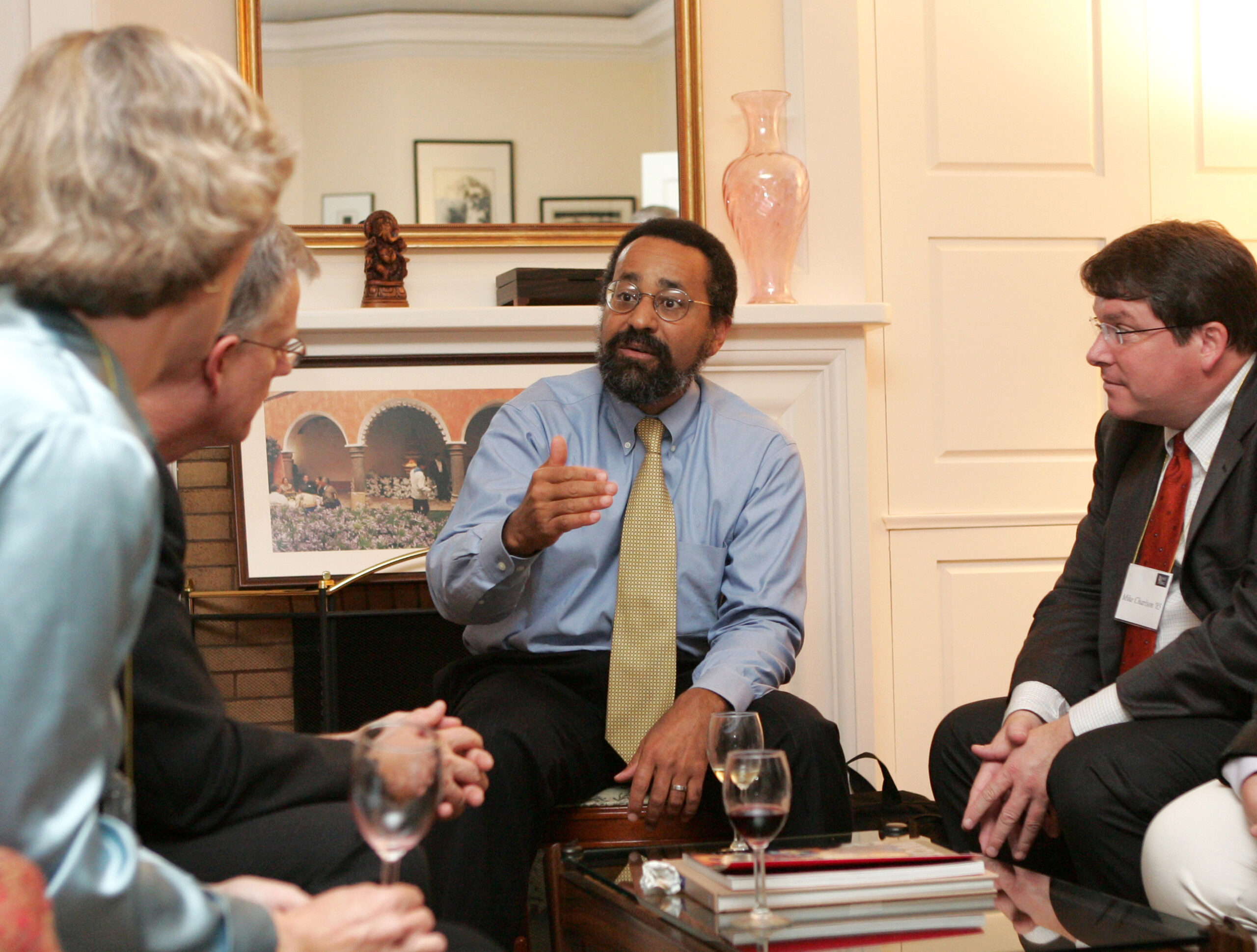 Christopher Edley gestures while he speaks while seated with a small group of four other men.