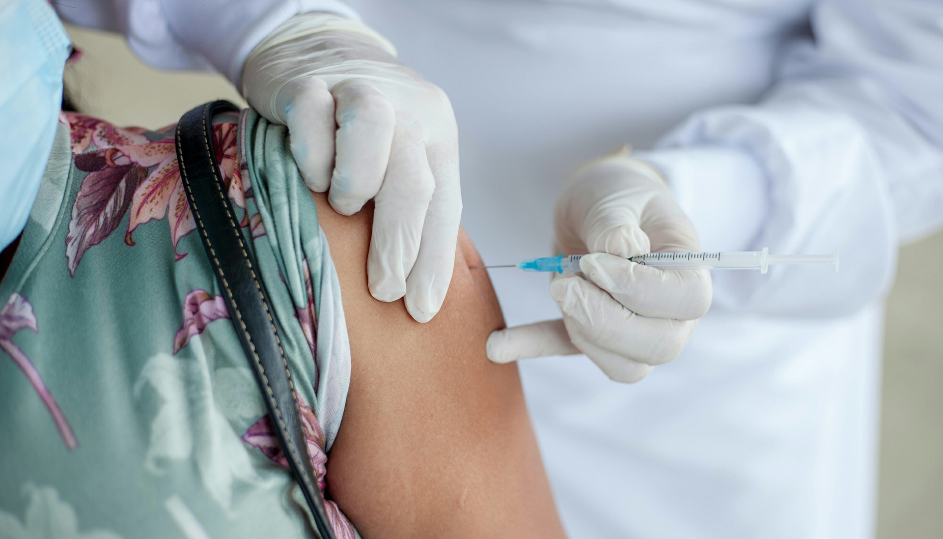 woman with sleeve rolled up being injected with a needle by a person in a white coat